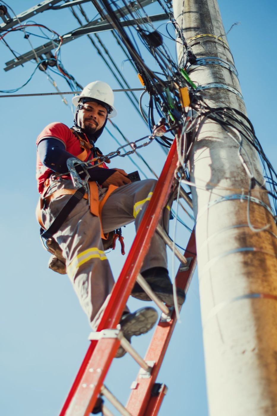 Utility technician maintaining electrical infrastructure from a safety ladder